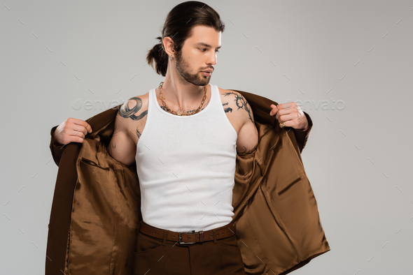 Long haired tattooed man wearing jacket isolated on grey