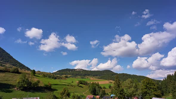 Rural landscape with pastures and forests, clouds in the blue sky in fast motion alt
