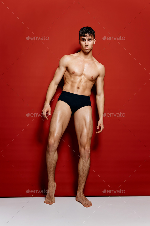 athletic guy in black panties nude torso bodybuilder Fitness red background  pose indoors Stock Photo by shotprime