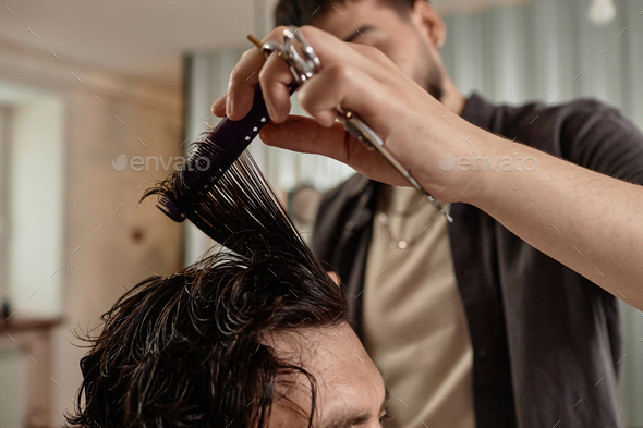 Barber cutting hair with scissors
