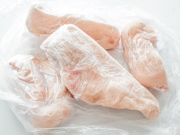 Frozen chicken breast in food plastic wrap or cling film.