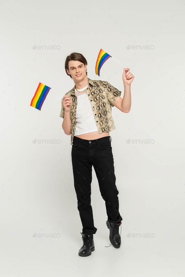 full length of positive pansexual model in black pants and snakeskin print blouse holding small lgbt
