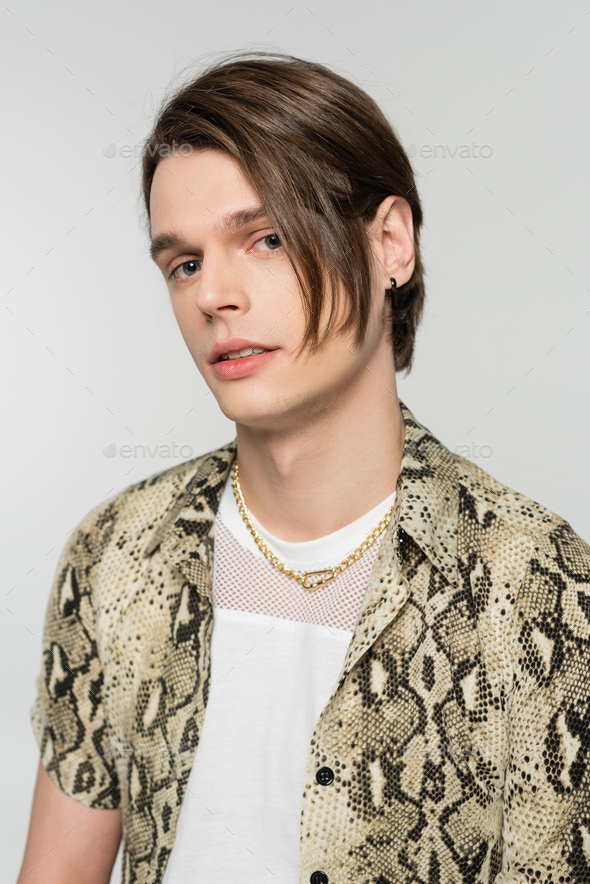 stylish bigender person in snakeskin print blouse and golden necklace looking at camera isolated on