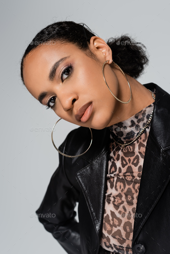 portrait of charming african american woman in trendy clothes and hoop earrings looking at camera
