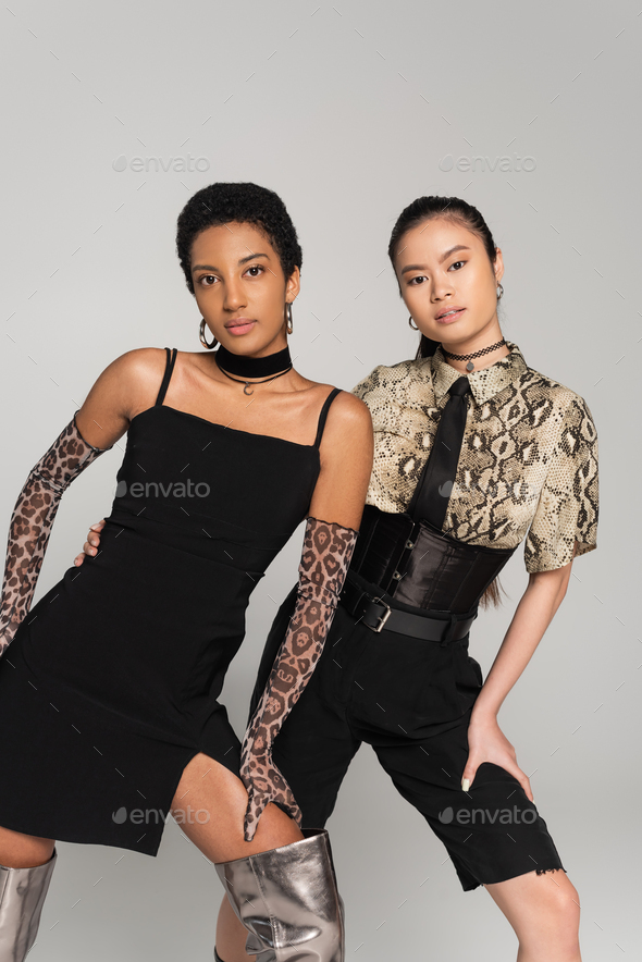 Trendy multiethnic women looking at camera while posing in clothes with animals prints isolated on