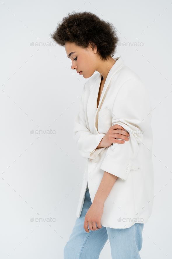 Side view of trendy african american woman rolling up sleeve of jacket isolated on grey