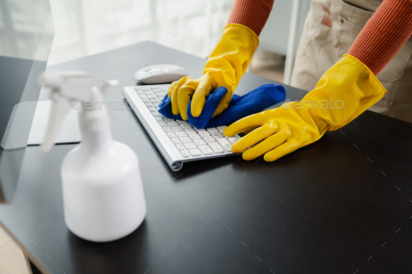 Cleaning staff wiping down office equipment, Wipe the keyboard clean with a towel and sanitizer, Wea