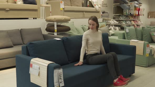 Female Customer Choosing Sofa in Shopping Center alt