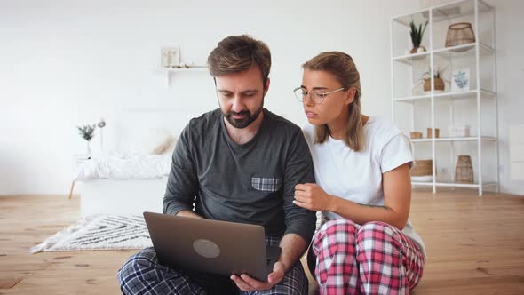 Young Couple in Pajamas Using Laptop in Cozy Bright Bedroom Slow Motion alt