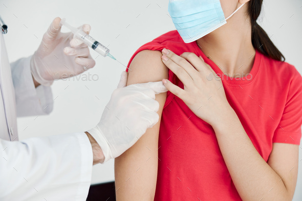 a doctor with a syringe in his hand makes an injection in the shoulder health covid vaccination