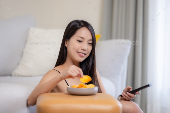 Woman watch TV and eat chips at home