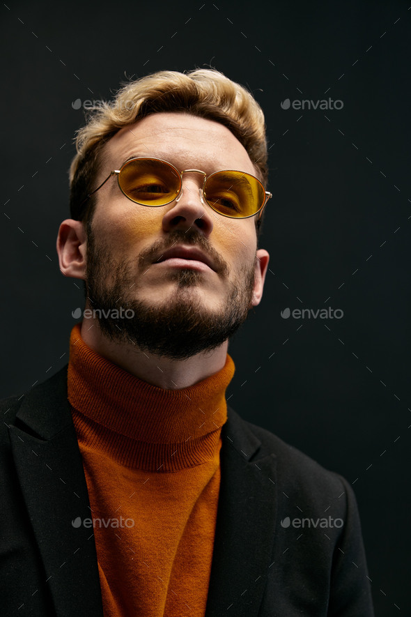 portrait of a fashionable man with glasses and an orange sweater jacket trend of the fall season new