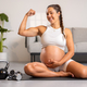 Smiling Strong Pregnant Expecting Mother Showing Off Muscles After Fitness Routine in Living Room - PhotoDune Item for Sale
