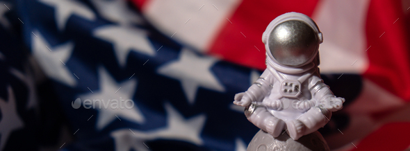 Plastic toy figure astronaut on American flag background Copy space. 50th Anniversary of USA Landing