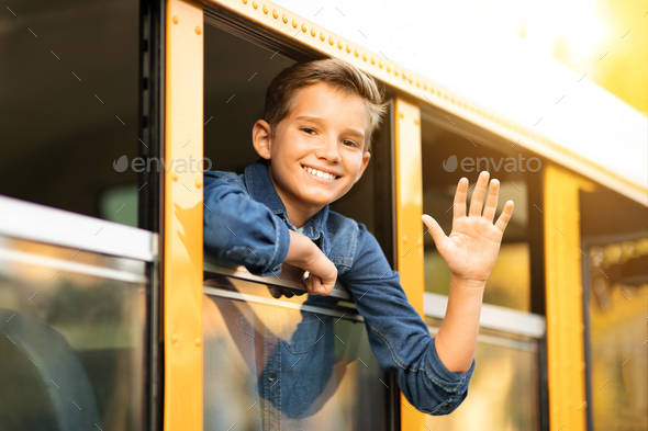 Happy preteen boy looking out of school bus window and waving hand ...