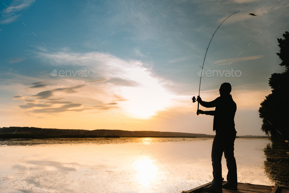 A fisherman silhouette fishing at sunset. Freshwater fishing