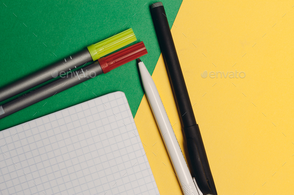 colored pens and markers on a bright background and a white notepad on the table