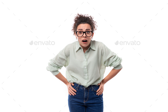 portrait of a young surprised teacher woman with curly black hair in glasses dressed in a shirt and