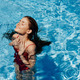 Happy woman swimming in the pool in red swimsuit with loose long