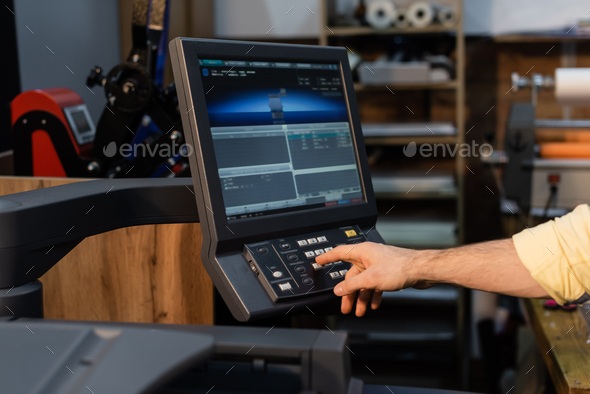 cropped view of man pressing button on panel near monitor in print center