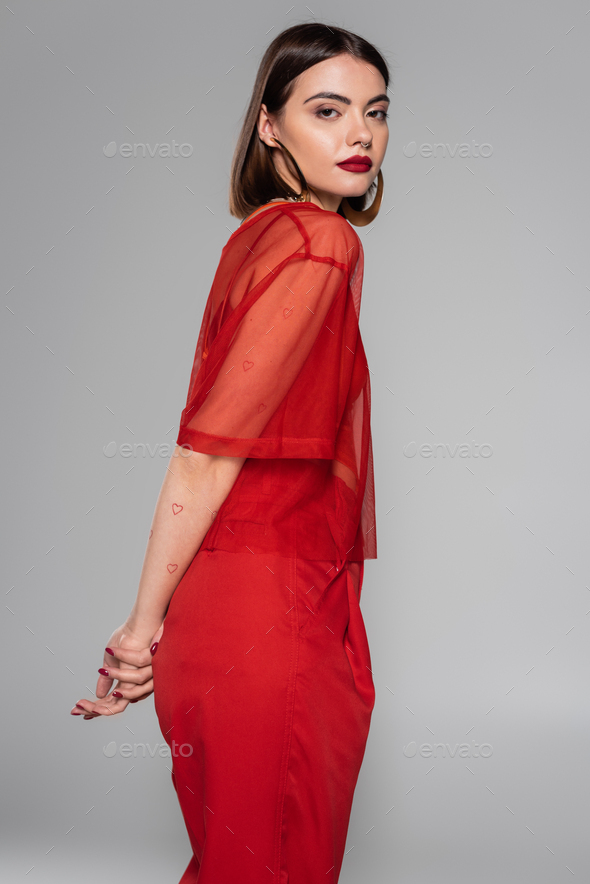 stylish red outfit, hoop earrings, tattooed and brunette woman with short hair and nose piercing