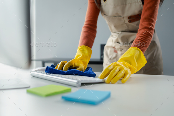 Cleaning staff wiping down office equipment, Wipe the keyboard clean with a towel and sanitizer, Wea