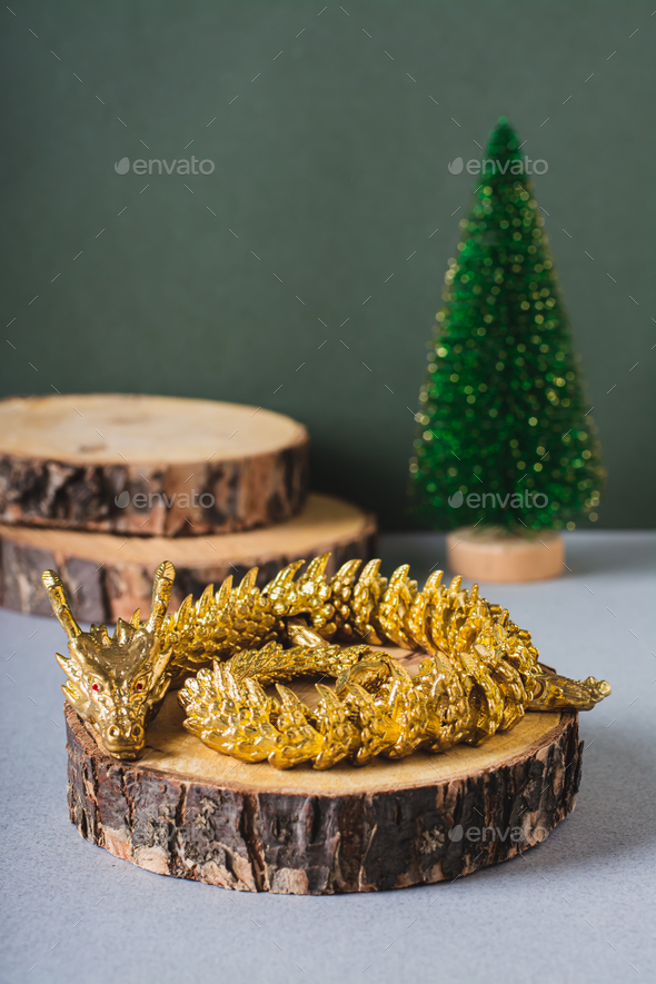 Metal dragon on a cut tree and fir tree on a green background for