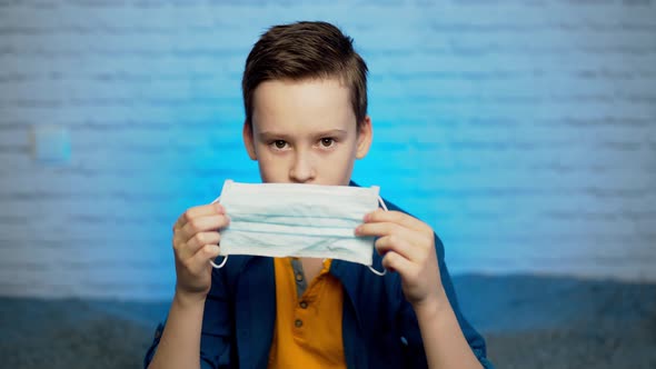 Beautiful boy puts on face medical mask against bacteria and viruses alt