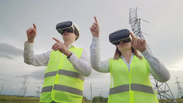 Two Engineers of Power Engineers in VR Glasses Move Their Hands Simulating the Operation of the alt