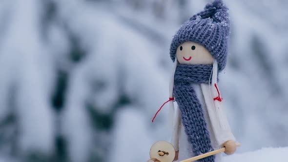 Angel Gnome in Scarf and Knitted Hat Skiing on Snowy Fir Branch Elf Toy on Skis in Snowy Landscape alt