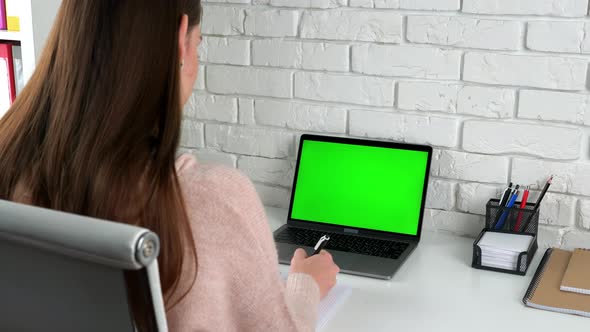 Green screen laptop woman student study writes information with pen in notebook alt