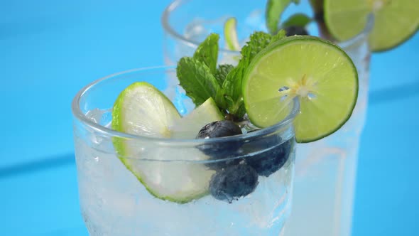 Shot of fresh mojito drink with ice cubes, lime slice, blueberry and mint leaves