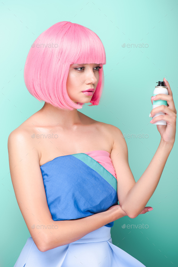 stylish young woman with pink bob cut holding coloring hair spray isolated on turquoise