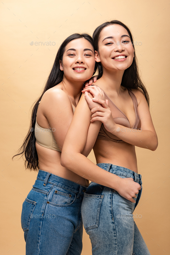 pleased asian woman in underwear smiling at camera isolated on beige Stock  Photo by LightFieldStudios