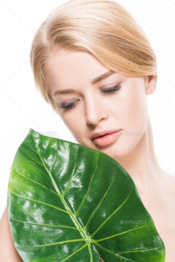 Pensive Naked Blonde Girl Looking At Green Tropical Leaf Isolated On