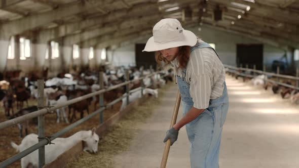 Young Man in Overalls Cleaning with Shovel Goat Farm alt