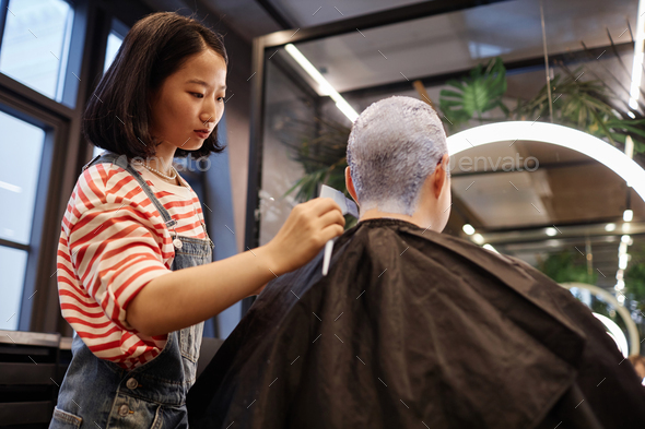 Hairstylist Bleaching and Dyeing Hair of Client in Beauty Salon