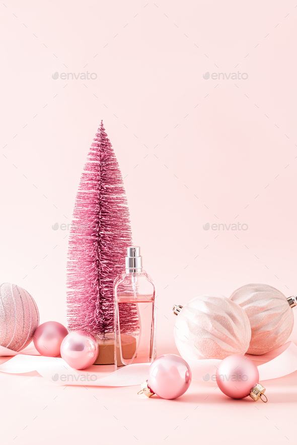 bottle of women\'s perfume or cosmetic spray on the background of a pink decorative Christmas tree