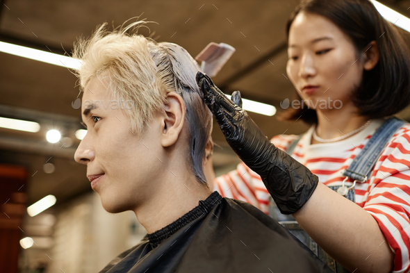 Young Asian Man in Beauty Salon with Hairstylist Bleaching Or Dyeing Hair
