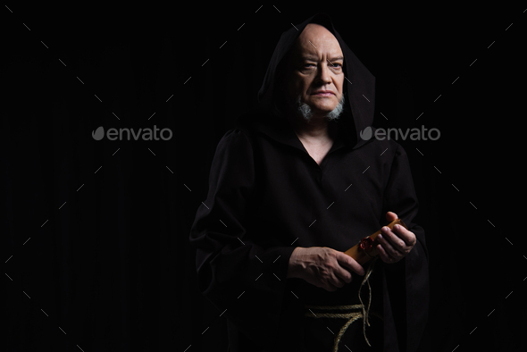 medieval monk in cassock holding parchment with wax seal isolated on black