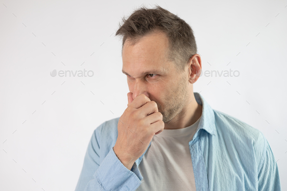 Young business man close up over gray background. Grabbing his nose with his fingers