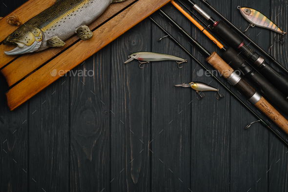 Fishing tackle - fishing spinning, hooks and lures on darken wooden  background. Top view Stock Photo by sedrik2007