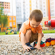 Little toddler boy playing with cars on pebbles on the playground. - PhotoDune Item for Sale