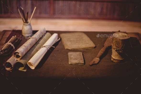 Closeup of parchment rolls with ancient tools on the table under the lights