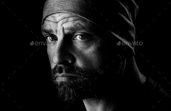 Grayscale shot of a portrait of a handsome attractive bearded anxious man with a wrinkled forehead