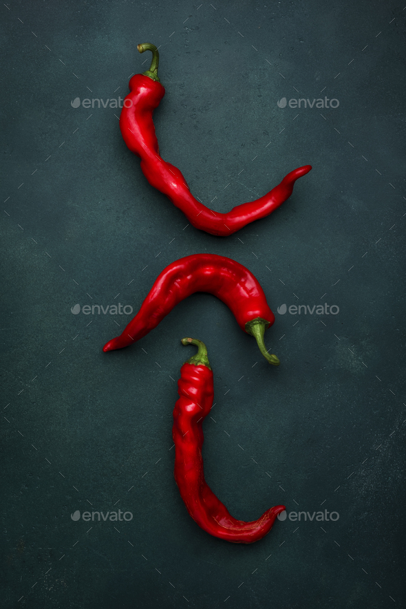Fresh red hot chili peppers on deep green background, minimalistic