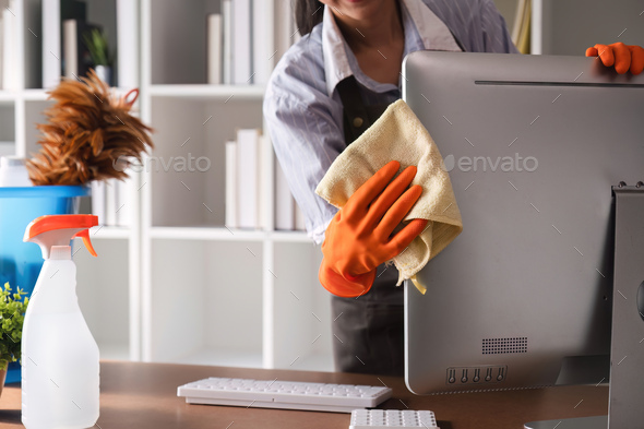 Young woman uses a cleaning cloth to disinfect the computer and equipment on the office table