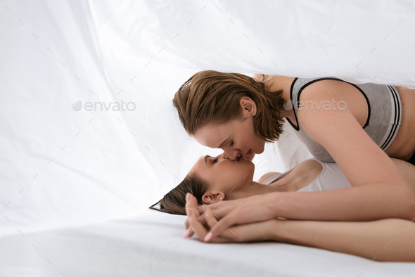 attractive sensual lesbians in black lingerie holding hands and lying on  bed Stock Photo