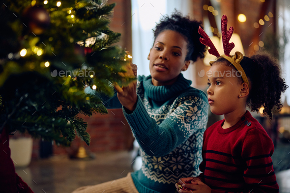 Mom and daughter decorate the Christmas tree Stock Photo by