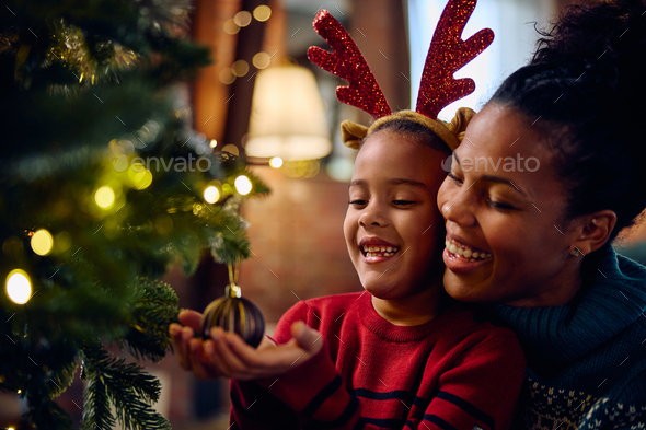 Mom and daughter decorate the Christmas tree Stock Photo by